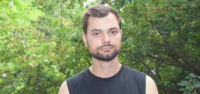 Porträt von Borys Hrachov im schwarzen Top vor grünen Bäumen