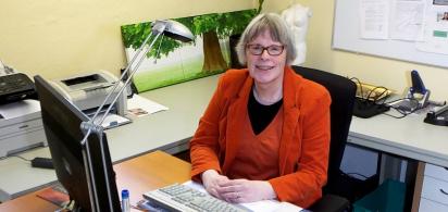 Person im roten Kostüm sitzt am Schreibtisch