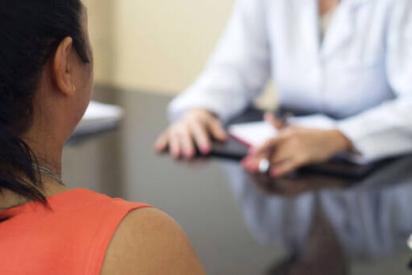 Rassismus im Gesundheitswesen: Rückenansicht einer BiPoC-Patient*in im Gespräch mit einer Person im weißen Kittel