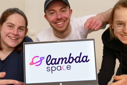 3 Personen mit einem Laptop, auf dem Bildschirm das Logo von lambda space